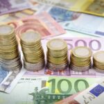 Banconote in euro e pile di monete, obbligazioni