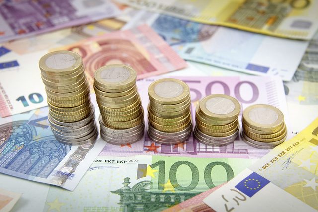 Banconote in euro e pile di monete, obbligazioni