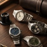 Orologi di lusso su una scrivania in legno accanto a una lente da orologiaio
