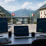Scrivania con tre schermi di grafici di borsa davanti a un valico di confine tra Svizzera e Italia (immagine generata con AI)